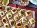 Sfiziose ricette con pasta sfoglia: quadratini dorati con olive, pesto e pomodori secchi, perfetti per un aperitivo.