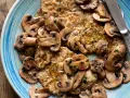 Scaloppine ai funghi, un piatto succulento con fettine di carne dorate e funghi champignon trifolati, guarnito con prezzemolo fresco.