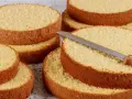 Dischi di pan di spagna sofficissimo con lievito, pronti per essere farciti. Una lama di coltello affilata riposa su uno strato.
