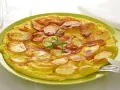 Frittata di patate dorata e gustosa, guarnita con rosmarino fresco, servita su un piatto verde.