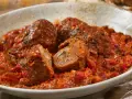 Involtini alla romana succulenti in un ricco sugo di pomodoro, con un interno visibile che rivela erbe aromatiche.