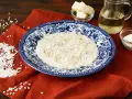 Un cremoso riso in bianco, condito con pepe nero, servito su un piatto decorato. Accanto, burro, olio e parmigiano grattugiato, ingredienti per un piatto semplice ma gustoso.