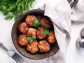 Polpette senza uova dorate in padella, guarnite con prezzemolo fresco. Un piatto gustoso e leggero, pronto per essere gustato.