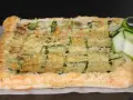 Torta salata con pasta sfoglia e zucchine a griglia, ricoperta di formaggio fuso e guarnita con fettine di zucchina fresca.