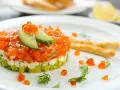 Tartare di salmone e avocado, un'idea per antipasti velocissimi senza cottura, guarnita con uova di pesce e cetriolo.