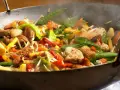 Straccetti di pollo saltati in padella con verdure colorate: piselli, carote, peperoni e germogli.