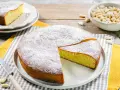 Torta soffice con farina di mandorle, spolverata di zucchero a velo. Un pezzo è già stato tagliato, pronto per essere gustato.