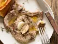 Succulente braciole di maiale cotte con aglio e erbe aromatiche, servite con pane croccante.