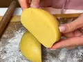 Mani che tengono un impasto giallo, profumato alla vaniglia, pronto per diventare una deliziosa pasta frolla senza burro.