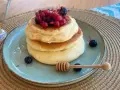 Pancake con albumi soffici, guarniti con frutti di bosco e miele. Un dolce leggero e goloso.