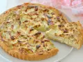 Una deliziosa torta salata con carciofi, dorata e invitante, con una fetta appena tagliata che mostra il ripieno cremoso.