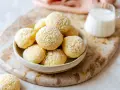 Biscotti da inzuppo spolverati di zucchero a velo in una ciotola, pronti per essere gustati con un bicchierino di latte.
