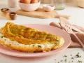 Frittata soffice e dorata, preparata in friggitrice ad aria, servita su un piatto rosa con erbe fresche.