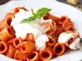 Rigatoni al sugo rosso con abbondante stracciatella cremosa e una fogliolina di basilico.