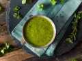 Una ciotola di vibrante salsa verde senza uovo, guarnita con peperoncino rosso tritato e erbe fresche. Perfetta per accompagnare i tuoi piatti preferiti.