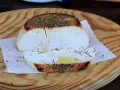 Ricotta al forno dorata e profumata con erbe aromatiche, servita su un tagliere di legno.