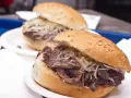 Panino con la milza, un classico street food siciliano, servito su un panino morbido con semi di sesamo e abbondante formaggio grattugiato.