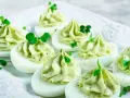 Uova ripiene per Pasqua, guarnite con crema verde e germogli freschi, un antipasto colorato e delizioso.