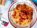 Un piatto di spaghetti alla chitarra con polpettine al sugo, serviti in un piatto decorato.