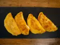 Quattro sofficini fatti in casa, dorati e croccanti, serviti su una pietra nera.