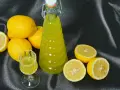 Limoncello fatto in casa: una bottiglia e un bicchierino di liquore giallo brillante, circondati da limoni freschi. La ricetta limoncello 1 litro alcool è pronta per essere gustata.