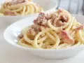 Un piatto di pasta alla gricia fumante, con guanciale croccante e pecorino romano grattugiato.