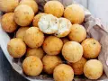 Un cesto pieno di croccanti polpette di ricotta, dorate e invitanti. Una è aperta, mostrando il morbido interno.