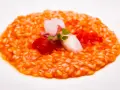 Un cremoso risotto al pomodoro, guarnito con calamari teneri, pomodorini e germogli freschi. Un piatto che celebra i sapori dell'Italia.