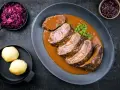 Fette fette di girello di vitello in salsa, accompagnate da cavolo rosso e canederli.