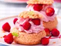 Deliziosa mousse di fragole su bignè, guarnita con fragoline di bosco e foglioline verdi.