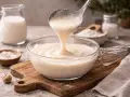 Besciamella senza latte cremosa versata in una ciotola di vetro. Ingredienti per una cucina senza lattosio.