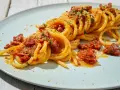 Spaghetti alla ghigliottina conditi con pomodorini secchi e pangrattato, un piatto invitante e saporito.