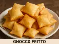 Piatto di gnocco fritto dorato e soffice, pronto per essere gustato. La ricetta originale per un sapore autentico.