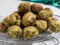 Pile di polpette ricotta e spinaci dorate e appetitose su una griglia metallica.