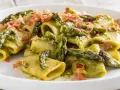 Paccheri conditi con una cremosa salsa verde e asparagi selvatici, guarniti con croccante prosciutto.