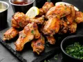 Alette di pollo dorate e succulente, cotte alla perfezione nella friggitrice ad aria, guarnite con prezzemolo fresco e spicchi di limone.
