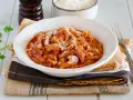 Un invitante piatto di trippa alla parmigiana, cosparso di formaggio grattugiato, pronto per essere gustato.