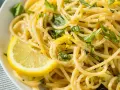 Un piatto invitante di spaghetti al limone, guarnito con scorza di limone e basilico fresco.