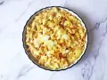 Piatto di mac and cheese fumante, con pasta penne cremosa e formaggio fuso, spolverato con paprika.