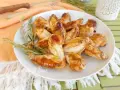 A plate of golden-brown, juicy chicken wings garnished with rosemary sprigs.