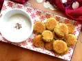 Falafel al forno dorati su un piatto decorato, accompagnati da una ciotola di salsa bianca con semi di cumino.