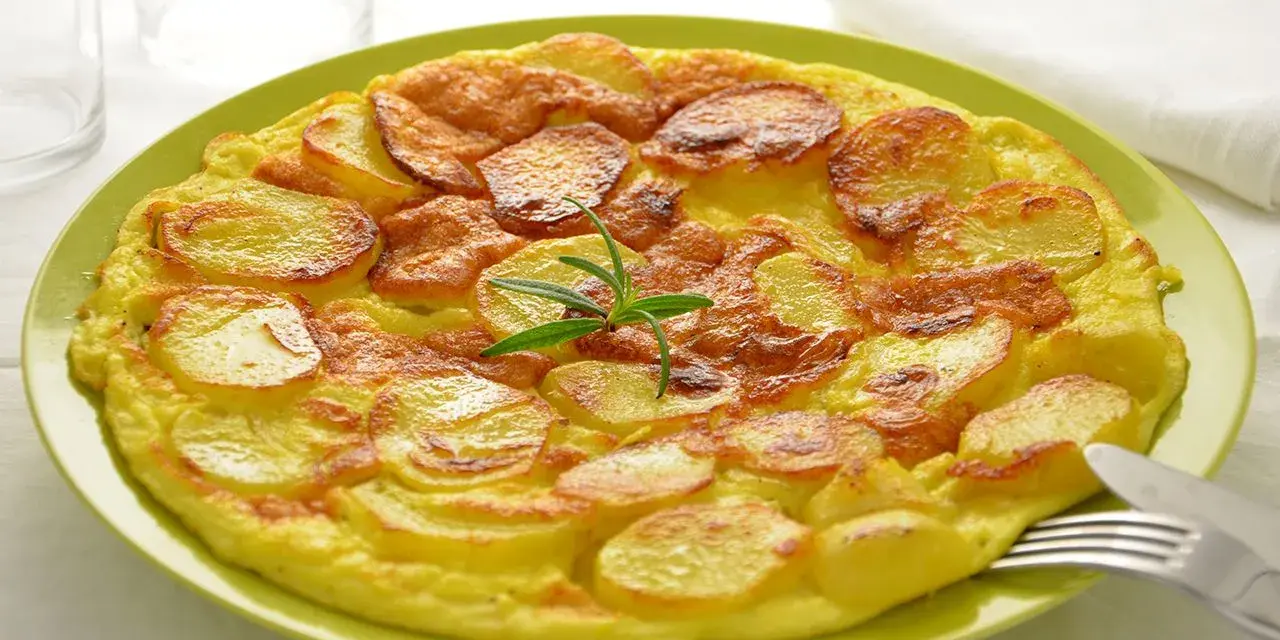 Frittata di patate dorata e gustosa, guarnita con rosmarino fresco, servita su un piatto verde.