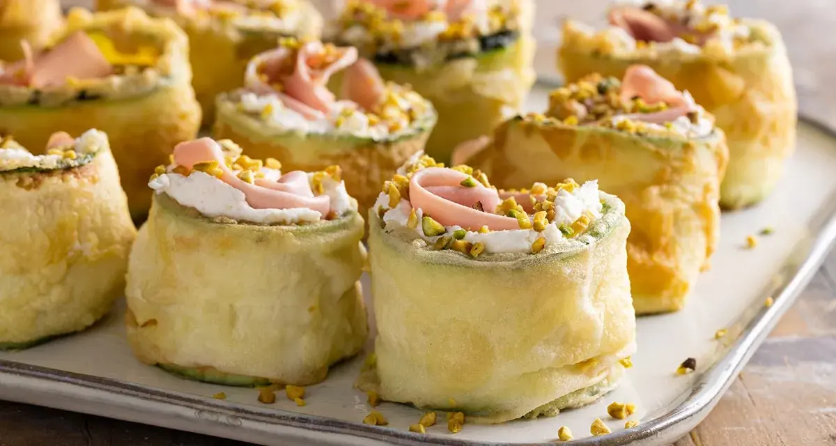 Rotolini di zucchine fritte con crema, prosciutto e pistacchi: stuzzichini veloci ed economici per aperitivo, perfetti per stupire gli ospiti.