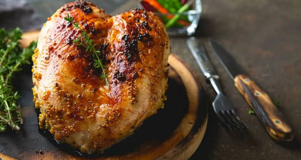 Petto di pollo al forno dorato e succulento, condito con senape e erbe aromatiche, pronto per essere gustato.