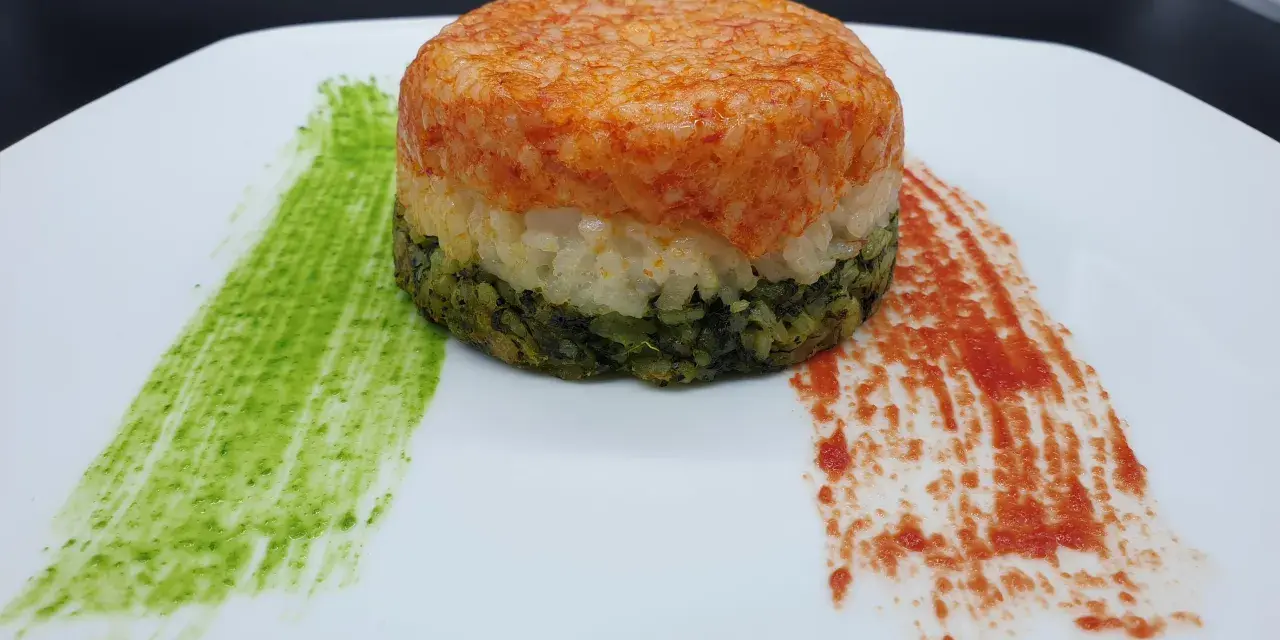 Un colorato timballo di riso a tre strati, con salse verdi e rosse che ricordano i colori di una bandiera.