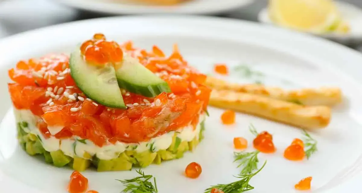 Tartare di salmone e avocado, un'idea per antipasti velocissimi senza cottura, guarnita con uova di pesce e cetriolo.