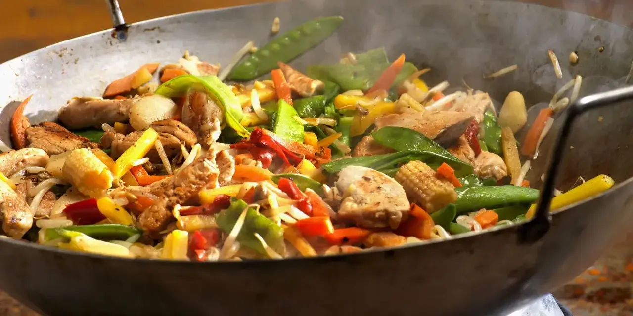 Straccetti di pollo saltati in padella con verdure colorate: piselli, carote, peperoni e germogli.