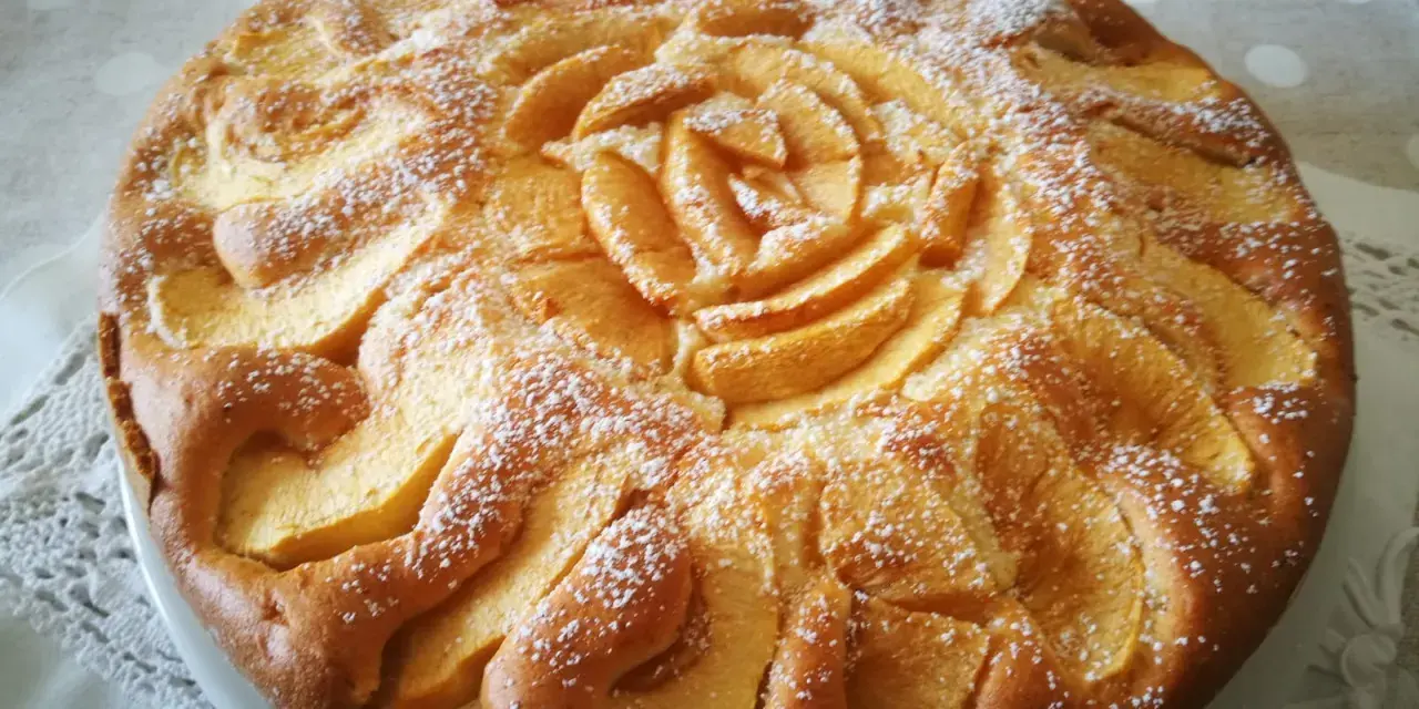 Deliziosa torta di mele senza glutine, decorata con mele a forma di rosa e spolverata di zucchero a velo.