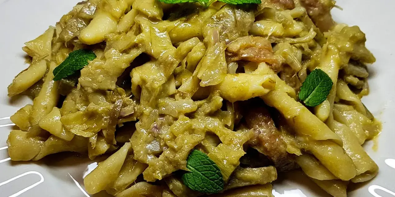 Pasta con carciofi cremosa, guarnita con foglie di menta fresca. Un piatto saporito e invitante.