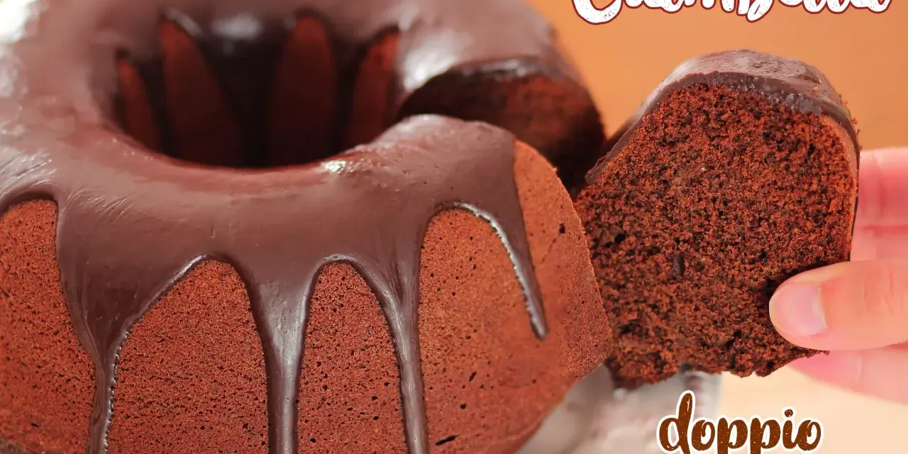 Ciambellone al cioccolato con glassa fondente. Una fetta viene sollevata, mostrando la consistenza soffice e il ricco colore del dolce.